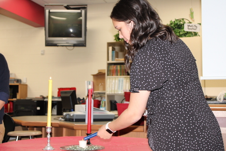 A student lighting the candle at the NAHS induction ceremony