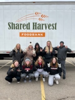 THS softball teams posing in front of the Shared Harvest truck