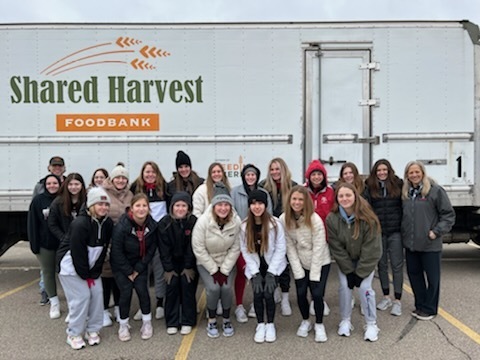 Softball team poses in front of the truck at Shared Harvest Foodbank.