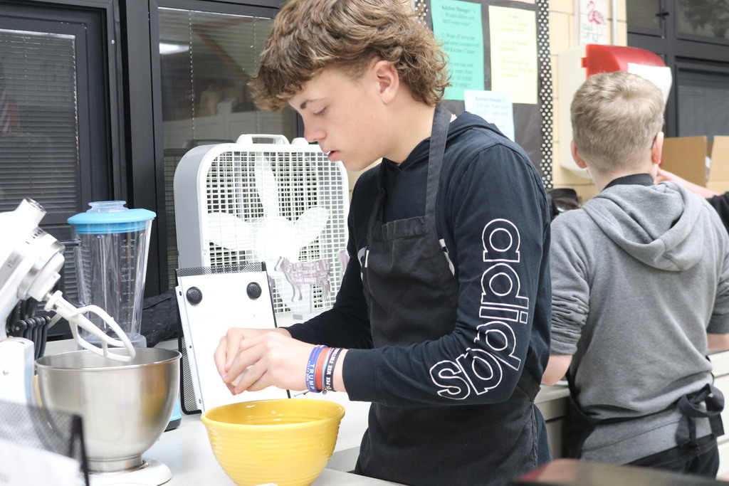 A TMS student cracking an egg as he makes cupcakes.
