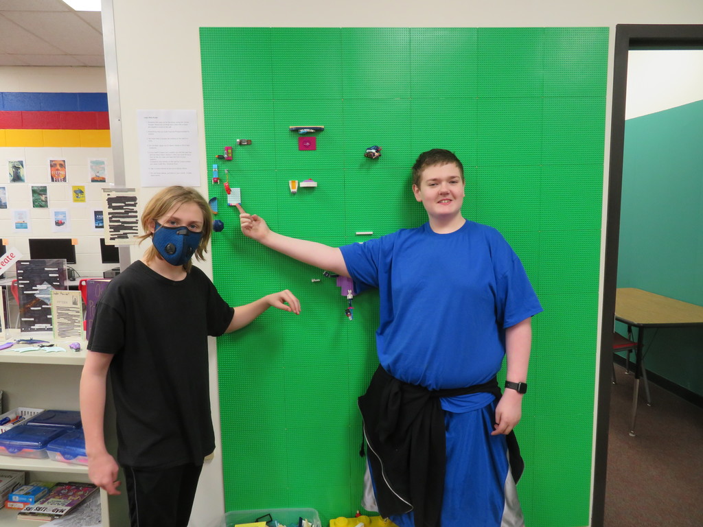 Two TMS students pose at the Lego wall to show off their creativity.
