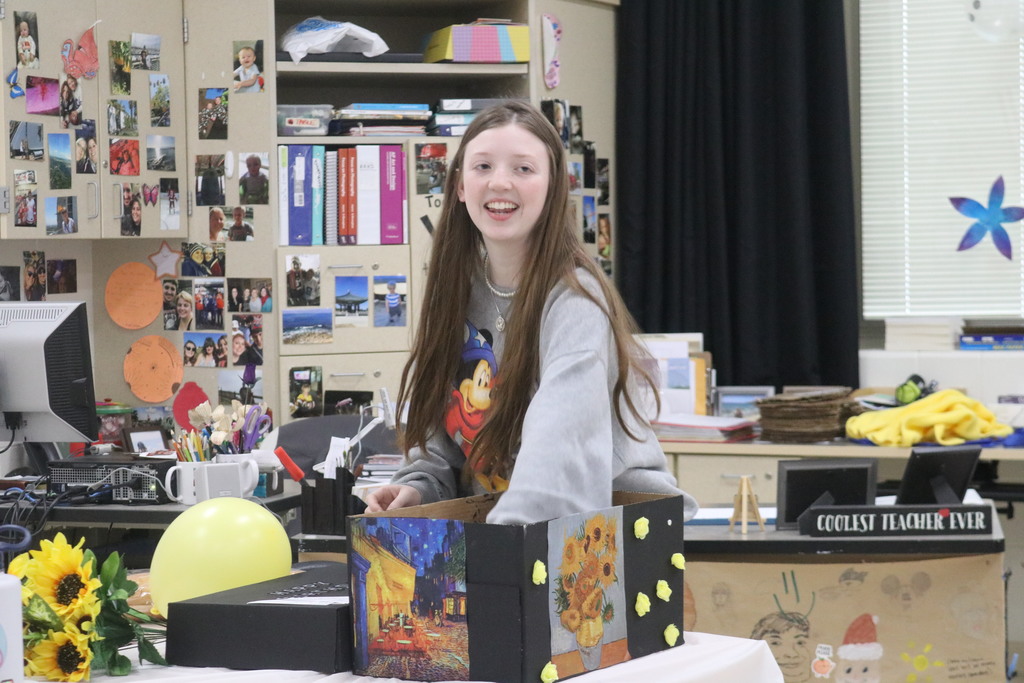 A THS student laughs as she reveals the birthday presents she selected for the artist she chose.