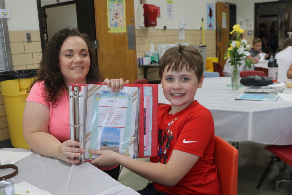 A proud TMS students shows his mom his poetry book.