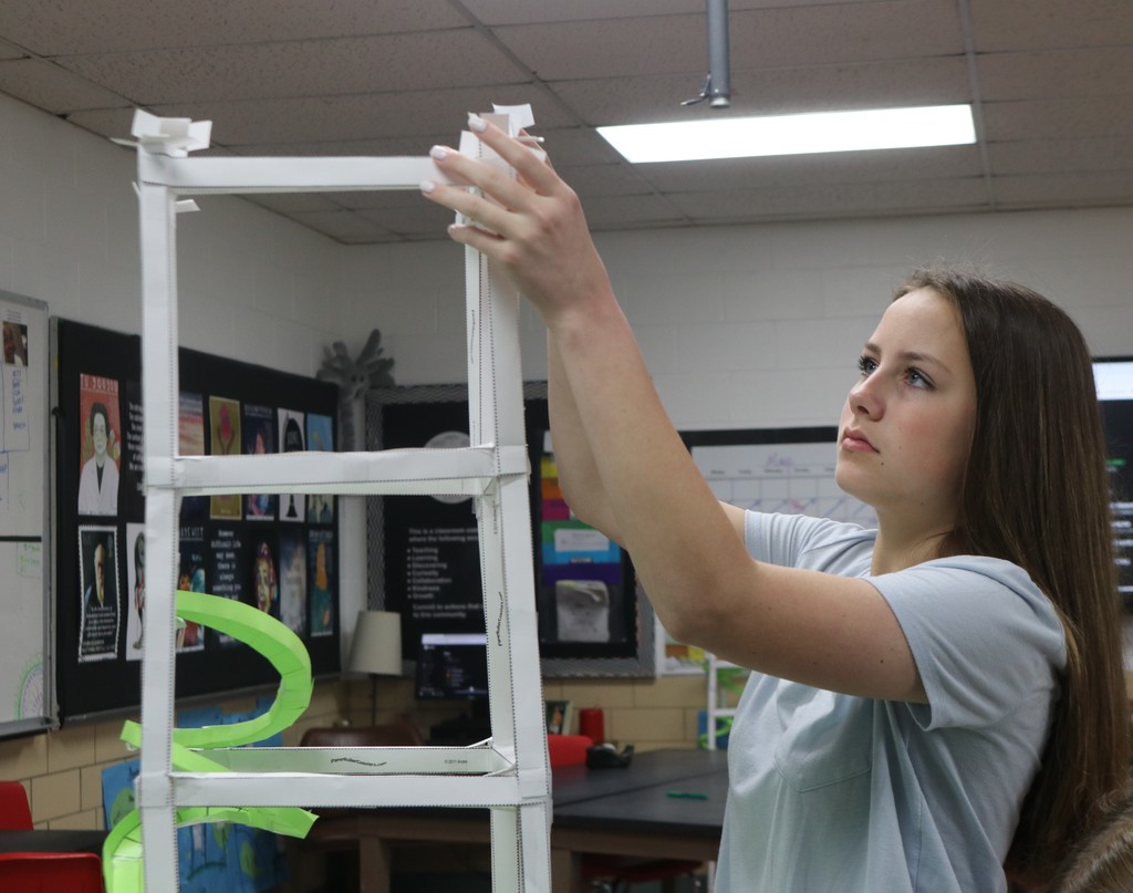 A TMS students adds a frame to her paper roller coaster.