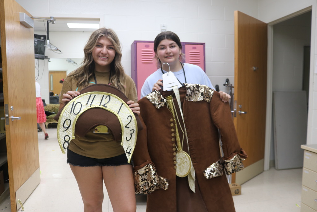 Two students hold up one of the costumes for the show.