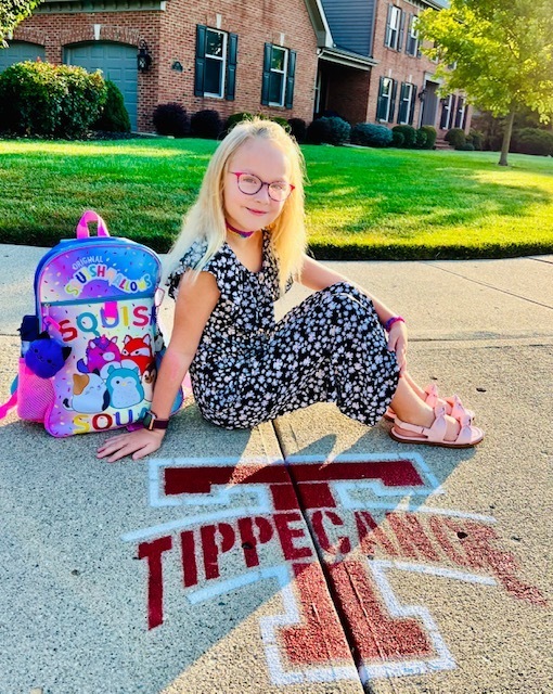 A  little girl poses on the first day of school.