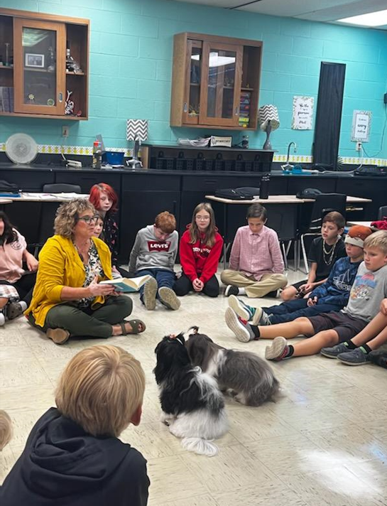 Two dogs and students listen to a story.