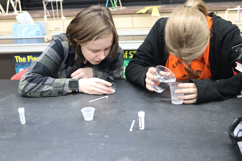 Two students are amazed at the chemical reaction of their lab work.  